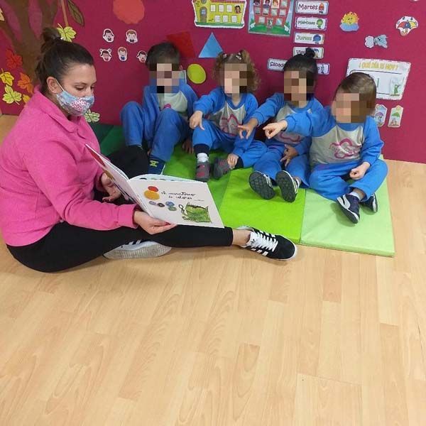 Una mujer está leyendo un libro a un grupo de niños.