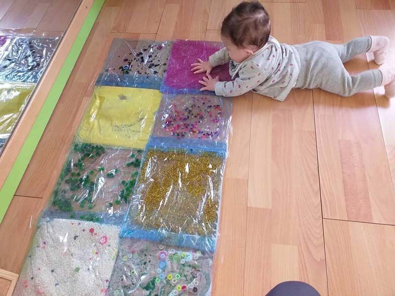 Un bebé está jugando con bolsas de plástico en el suelo.