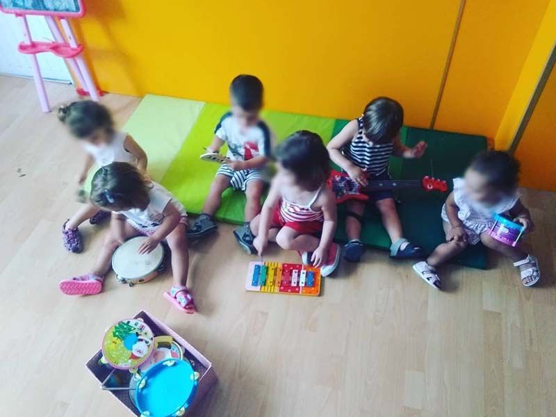Un grupo de niños está sentado en el suelo tocando instrumentos musicales.