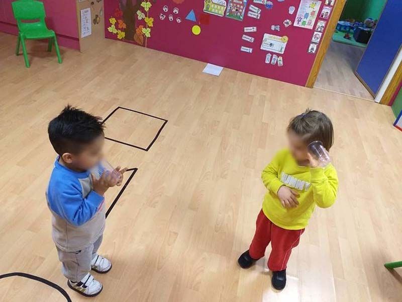 Dos niños pequeños están parados en una habitación y uno lleva una camiseta amarilla que dice ejército.