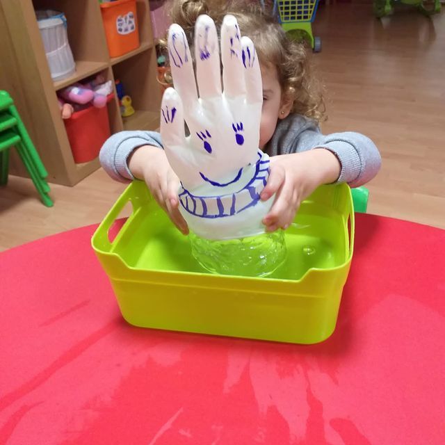 Un niño está jugando con un guante de plástico que tiene una cara sonriente dibujada en él.