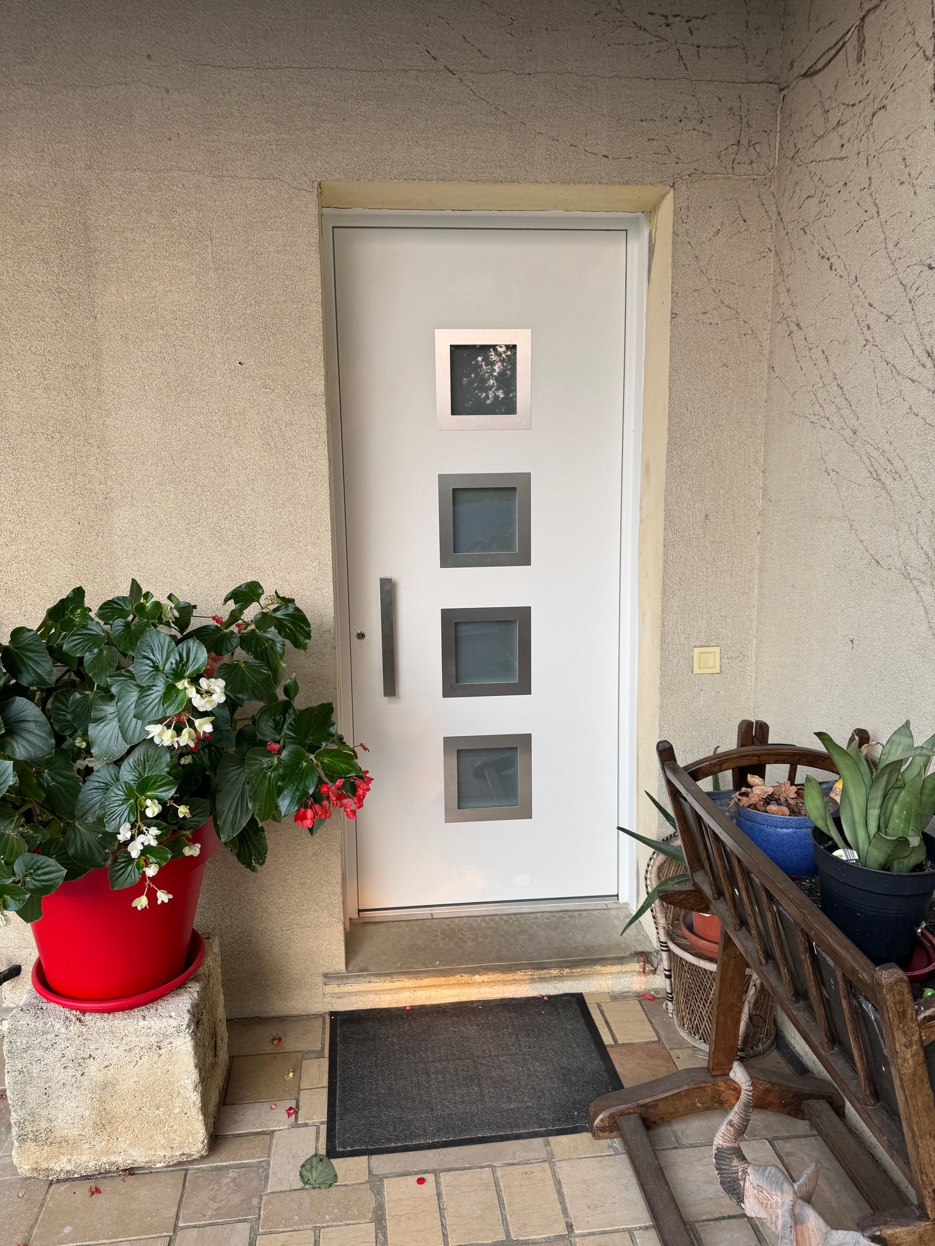 Porte d'entrée blanche à panneaux de verre carrés.
