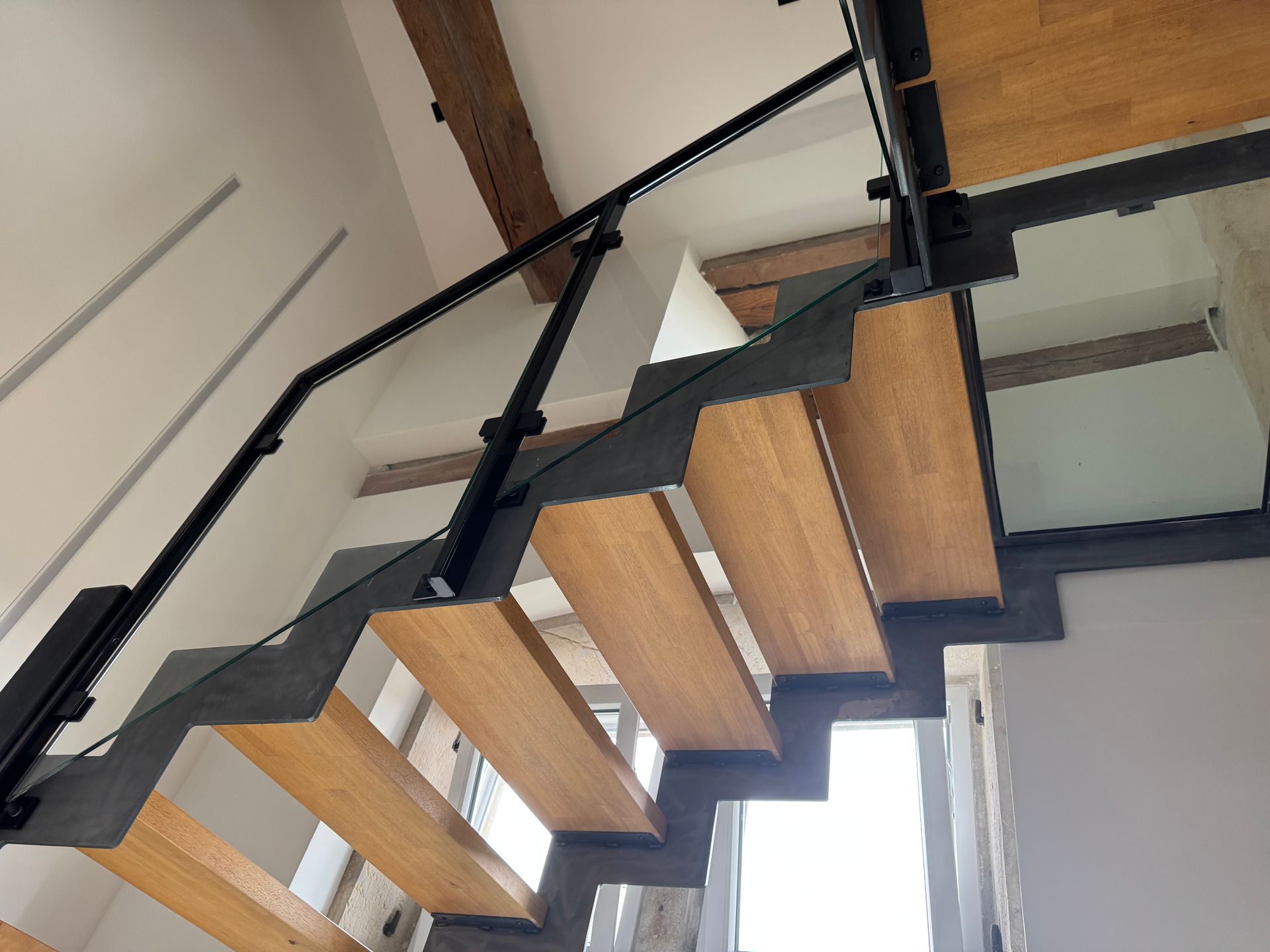 Escalier moderne en bois avec supports et rampe en métal noir.