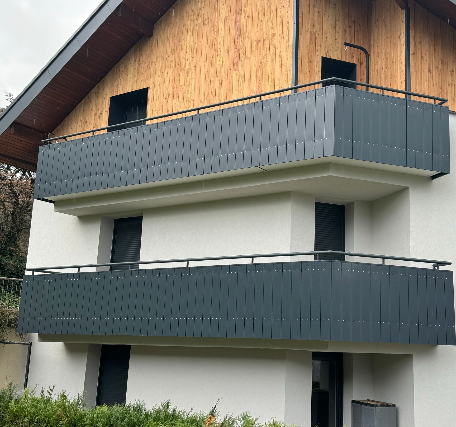 Bâtiment de deux étages avec balcons gris.