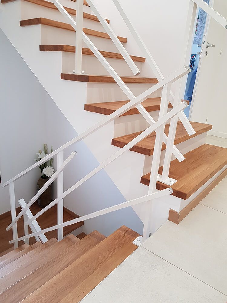 Escalier en bois avec rampe blanche contre mur blanc.
