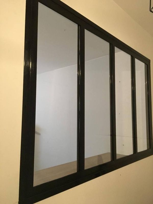 Des panneaux miroirs à cadre noir sont encastrés dans un mur beige.