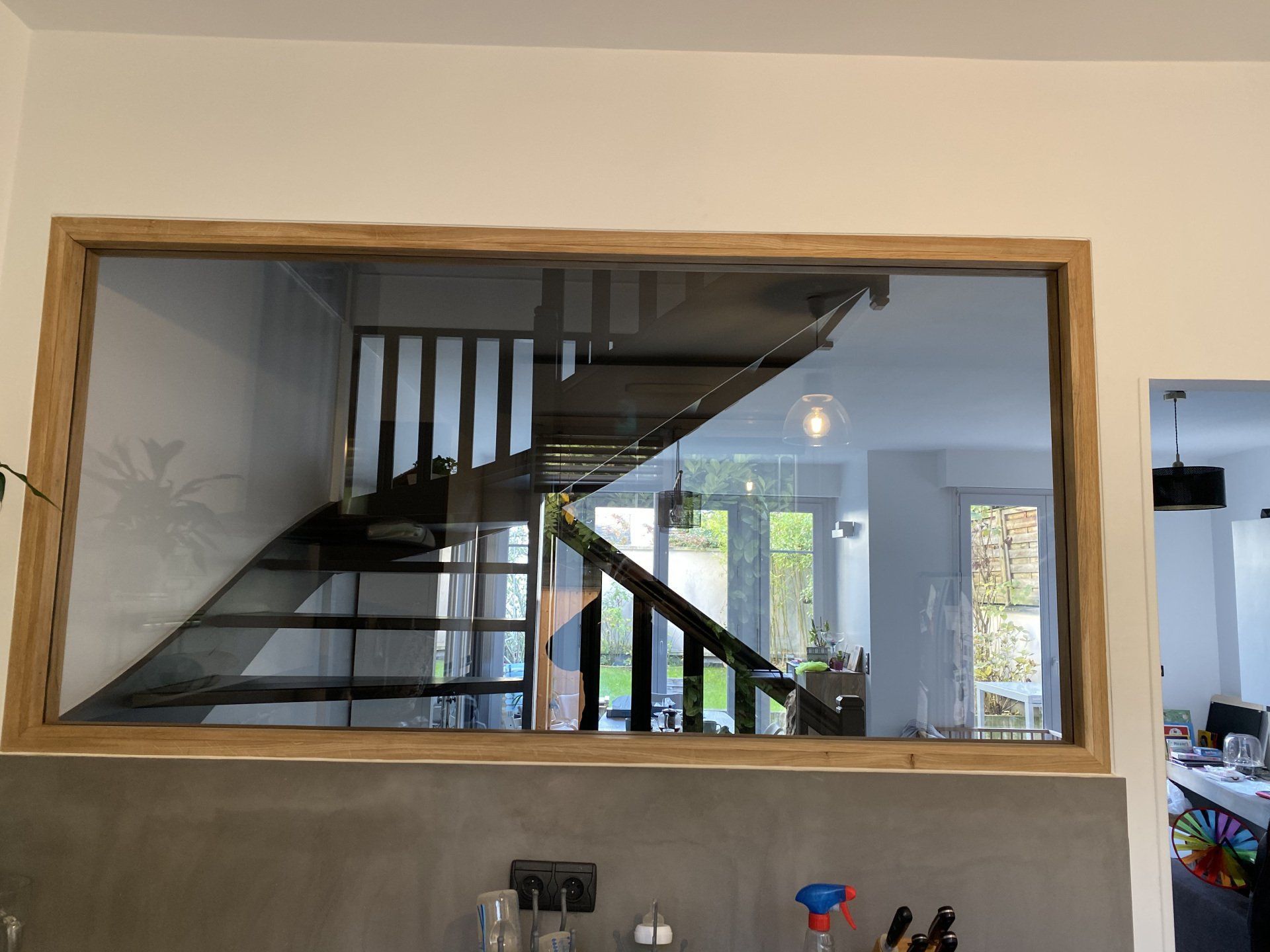 Grande fenêtre rectangulaire à cadre en bois, donnant sur un escalier et un intérieur lumineux.