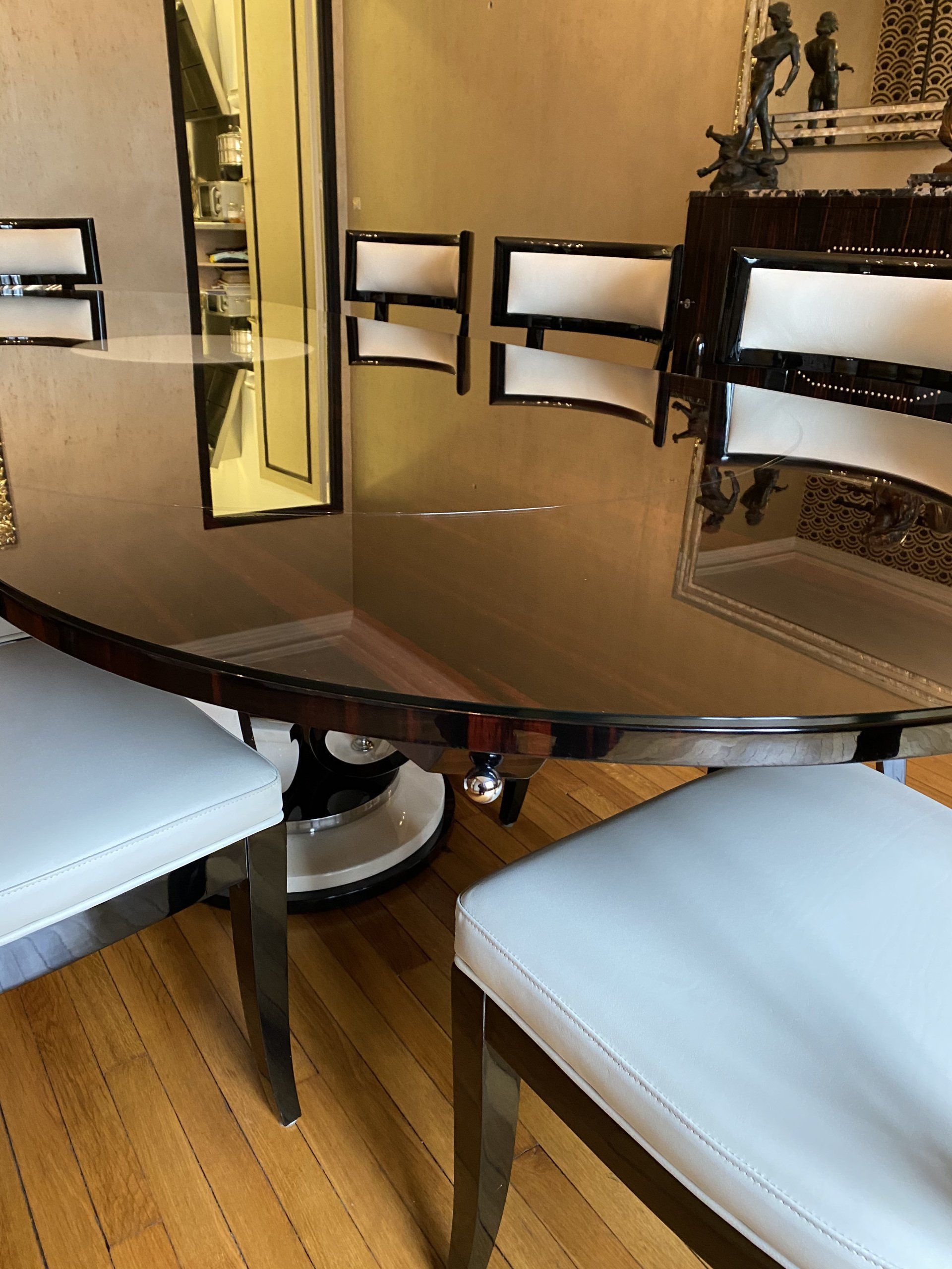 Table de salle à manger ovale avec six chaises blanches rembourrées.