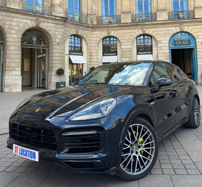 Une berline sport noire brillante est garée devant un bâtiment historique en pierre.