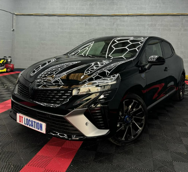 Berline sportive noire à hayon exposée dans un showroom, finition brillante, sur un présentoir rouge et noir.