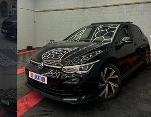 Volkswagen hatchback noire dans un showroom intérieur, vue de l'avant gauche.
