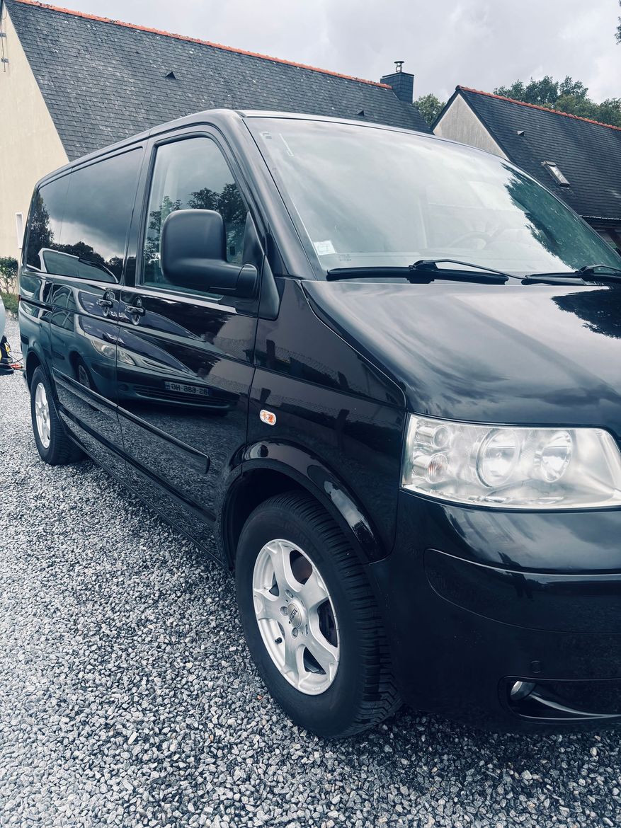 Une camionnette noire garée sur une allée mouillée à côté d'une maison par une journée pluvieuse