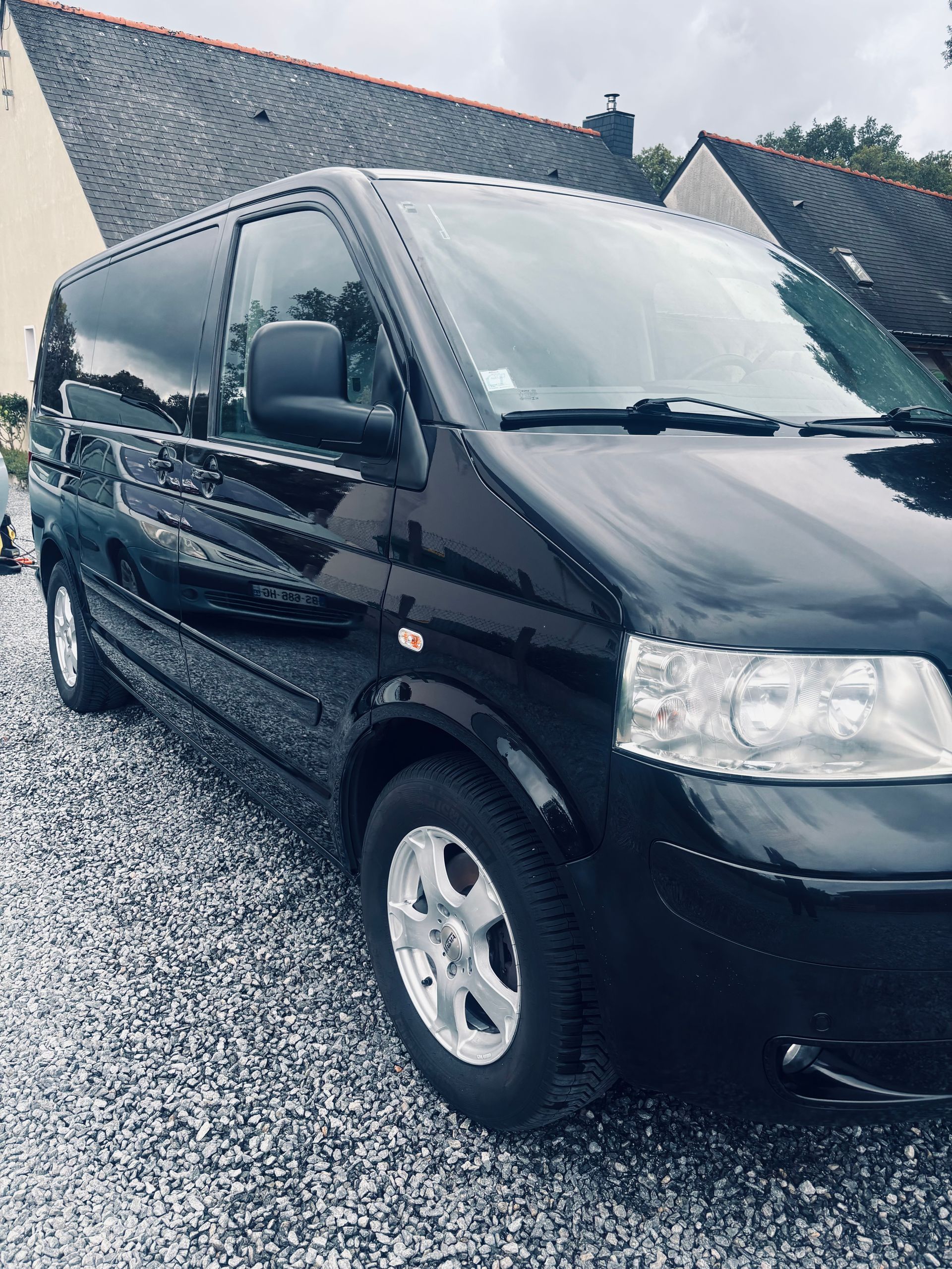 Une camionnette noire garée sur une allée mouillée à côté d'une maison par une journée pluvieuse
