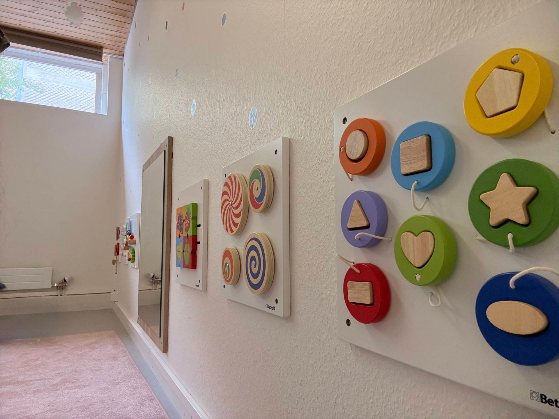 Flurwand mit farbenfrohen, runden Kinderkunstwerken in einem hellen Raum