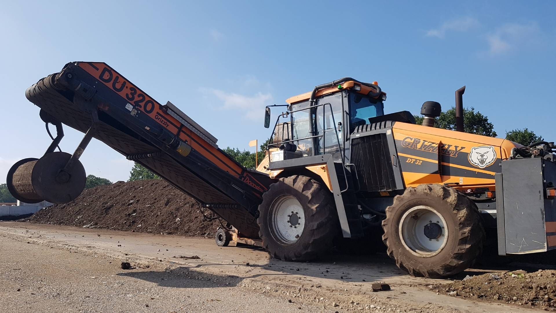 Ein großer oranger Traktor mit einem daran befestigten Förderband