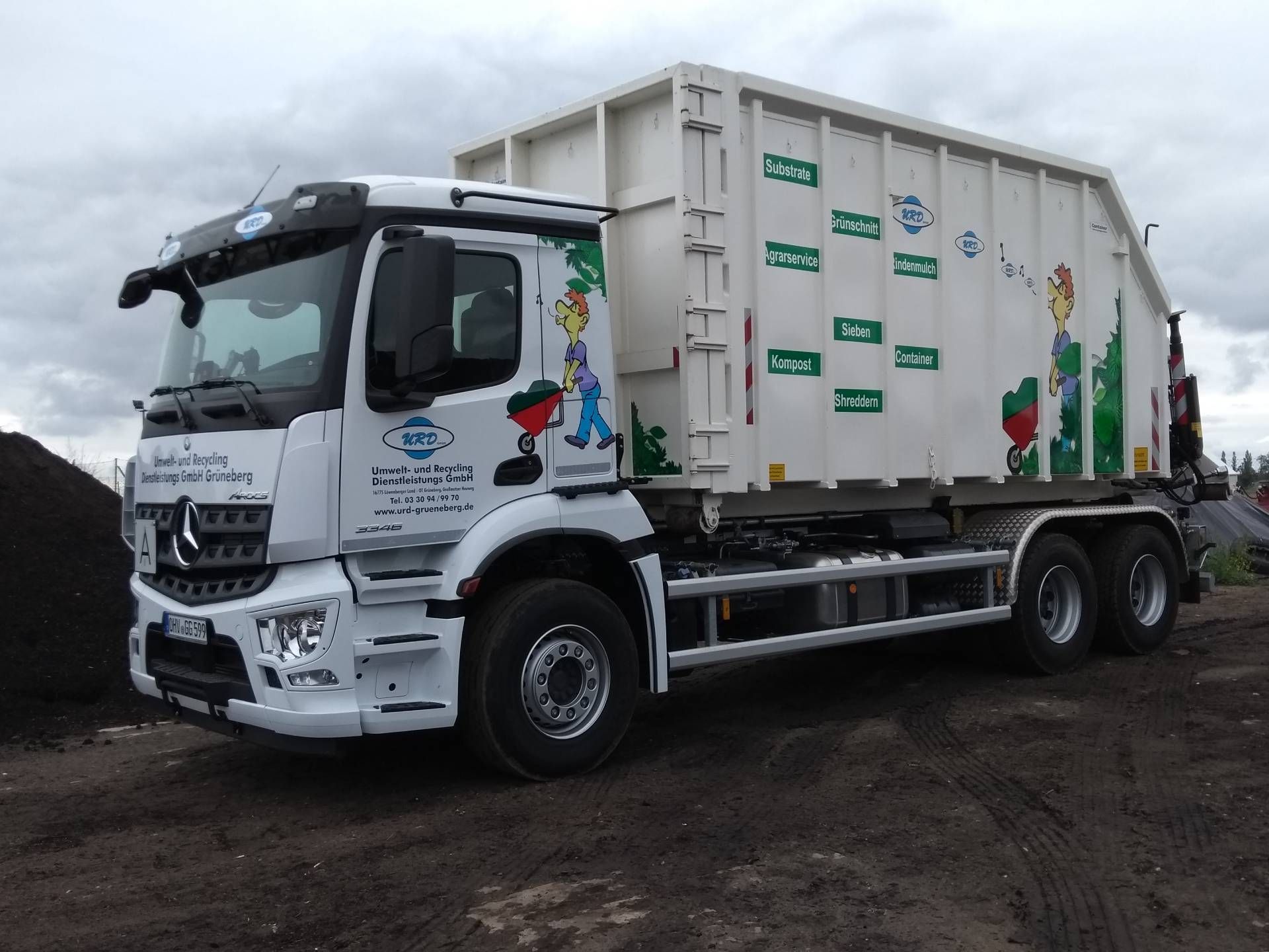 Ein weißer Müll-Container-LKW steht auf einem Feld.