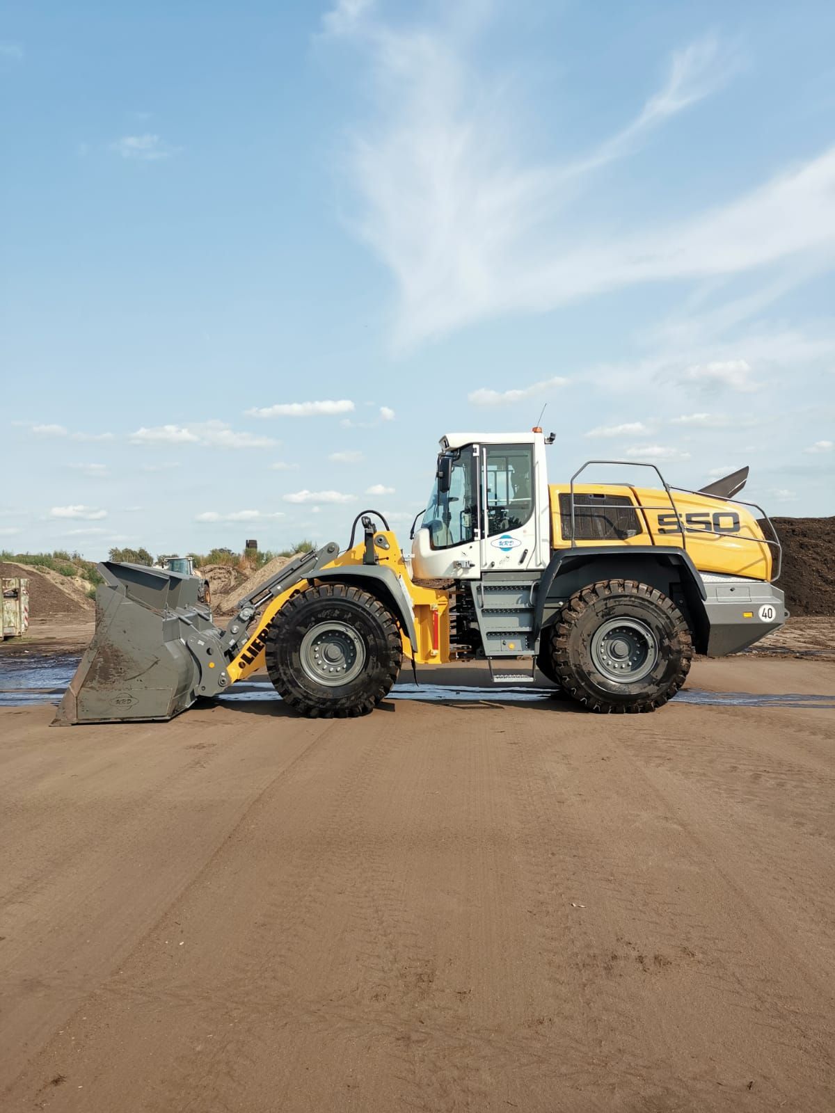 Ein gelb-weißer Radlader steht auf einem Feld.