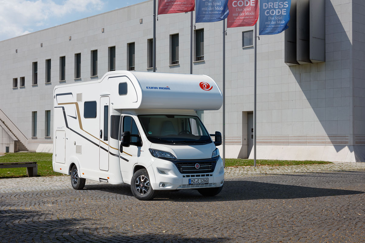 Ein weißes Wohnmobil ist vor einem Gebäude geparkt.