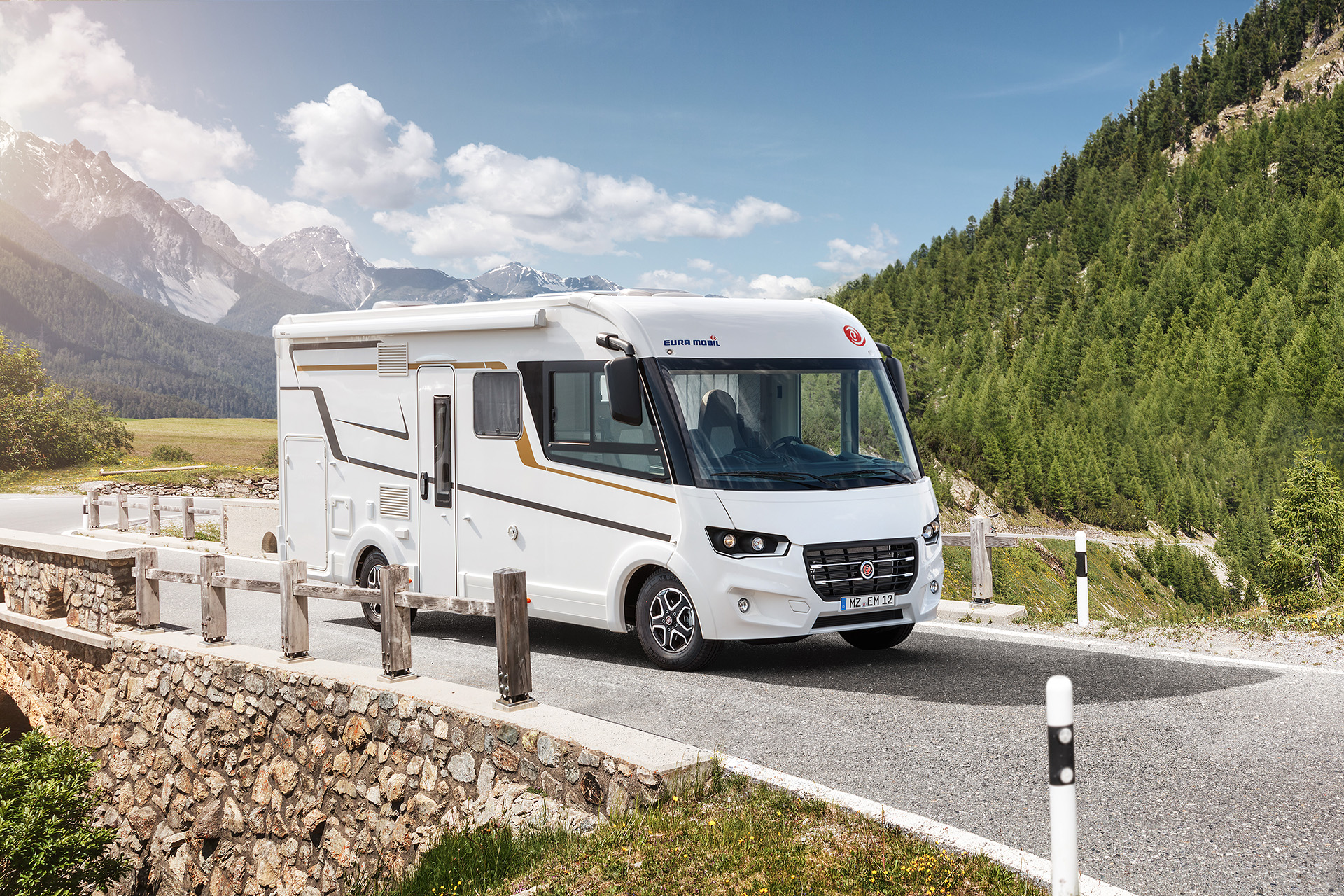 Ein weißes Wohnmobil fährt eine Bergstraße hinunter.