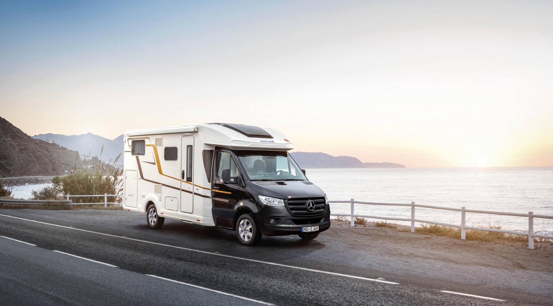 Ein Wohnmobil fährt eine Straße am Meer entlang.