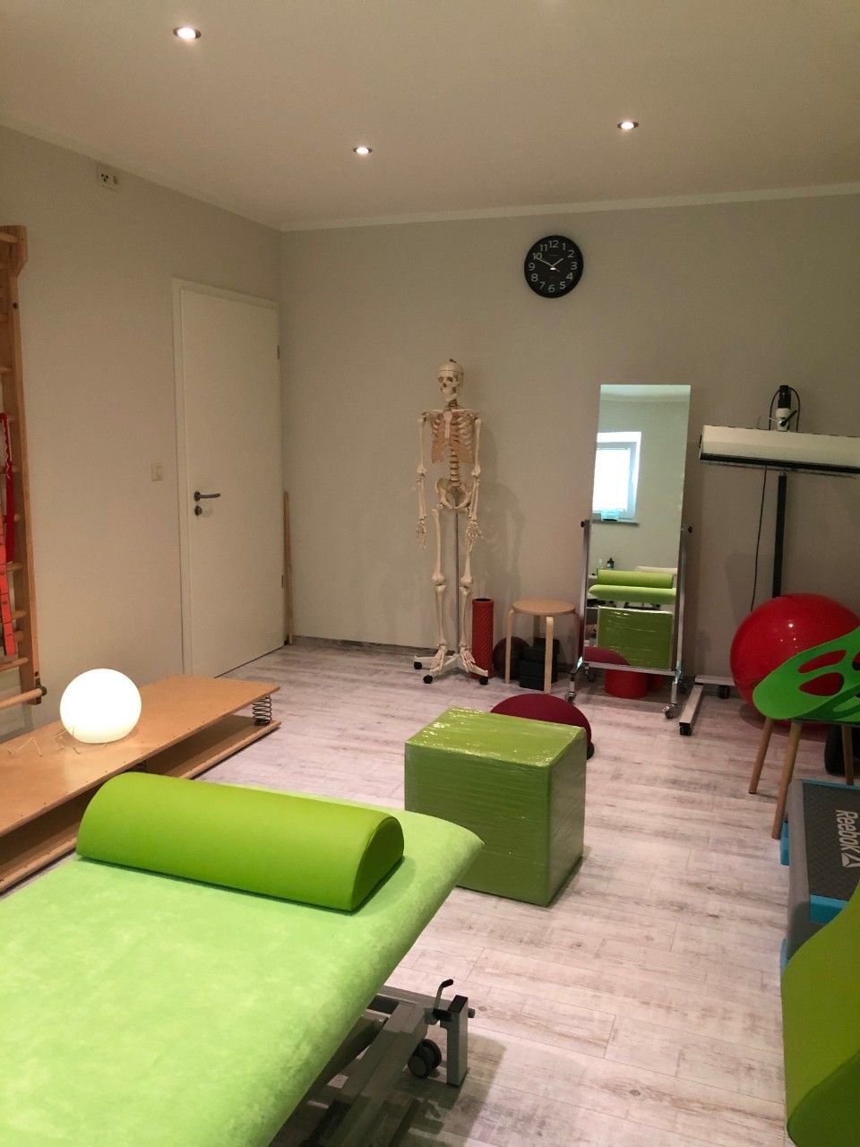 Behandlungsraum in der Physiopaxis mit grüner Liege, grünem Hocker