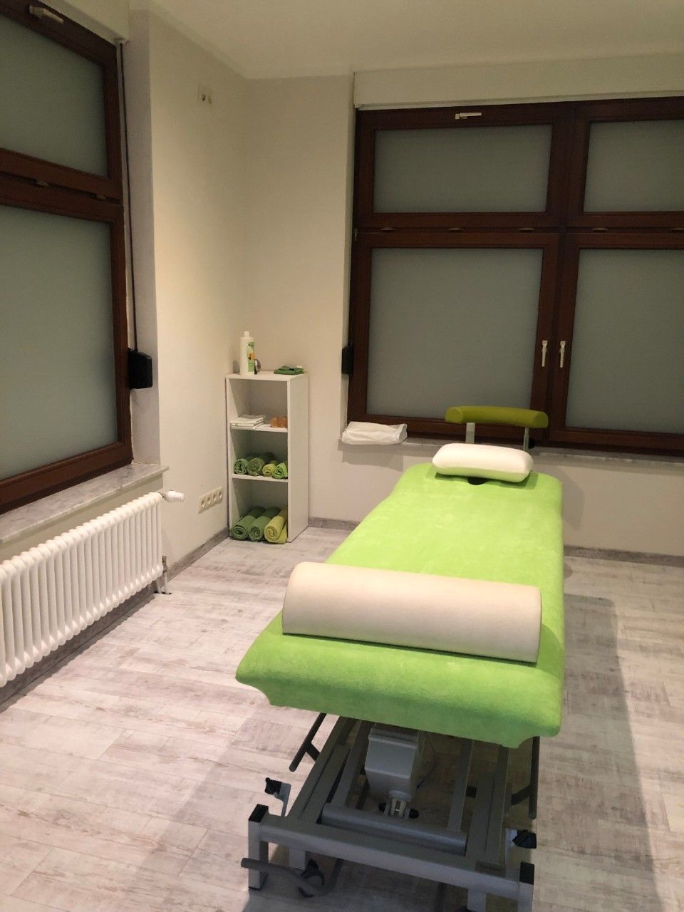 Grüne Behandlungsliege in einem Raum mit hellem Boden
