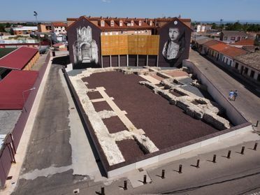 Vista aérea de un patio en la azotea con grandes murales en blanco y negro y edificios de ladrillo a su alrededor.