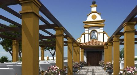Iglesia amarilla con campanario blanco al final de un sendero de piedra bajo una columnata.