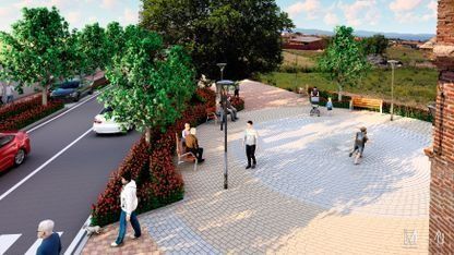 Plaza pavimentada con algunas personas caminando junto a una calle arbolada y una zona de estar ajardinada.