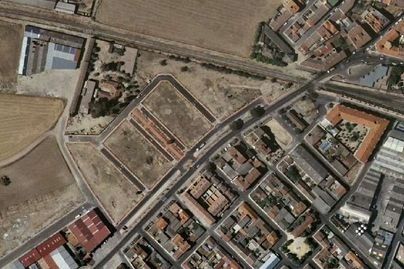 Vista aérea de las afueras de una ciudad con carreteras, edificios y campos abiertos.