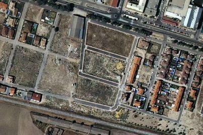 Vista aérea de un solar urbano vacío rodeado de calles y edificios de apartamentos.