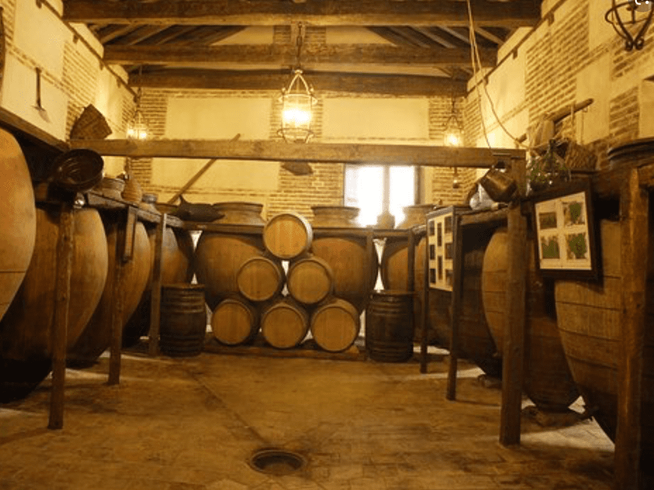 Bodega con iluminación tenue, con barriles de roble apilados y faroles colgantes.