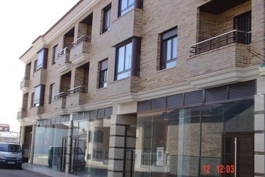 Edificio de apartamentos moderno con escaparates de cristal en la planta baja y balcones en la planta superior.