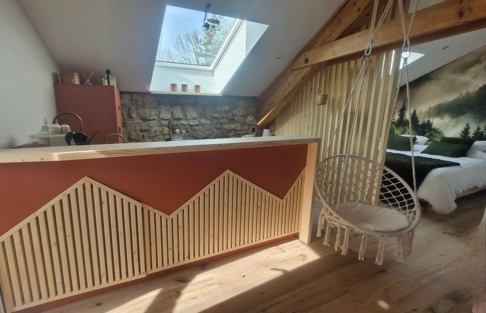 Intérieur avec mur d'accent en bois et chaise suspendue, ouvert sur la chambre avec peinture murale et lit.