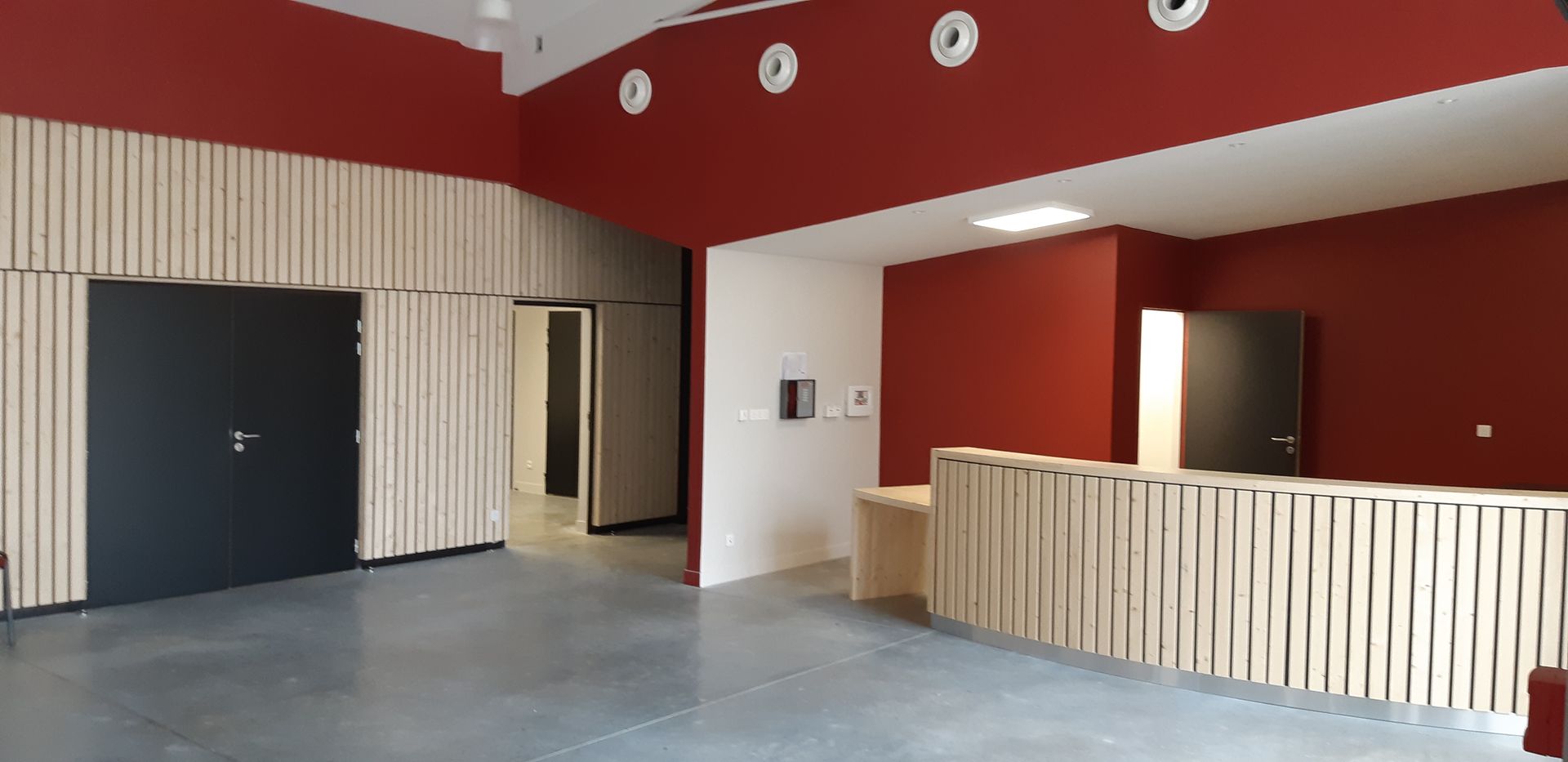 Intérieur d'un espace de réception avec murs rouges, boiseries et sol gris.
