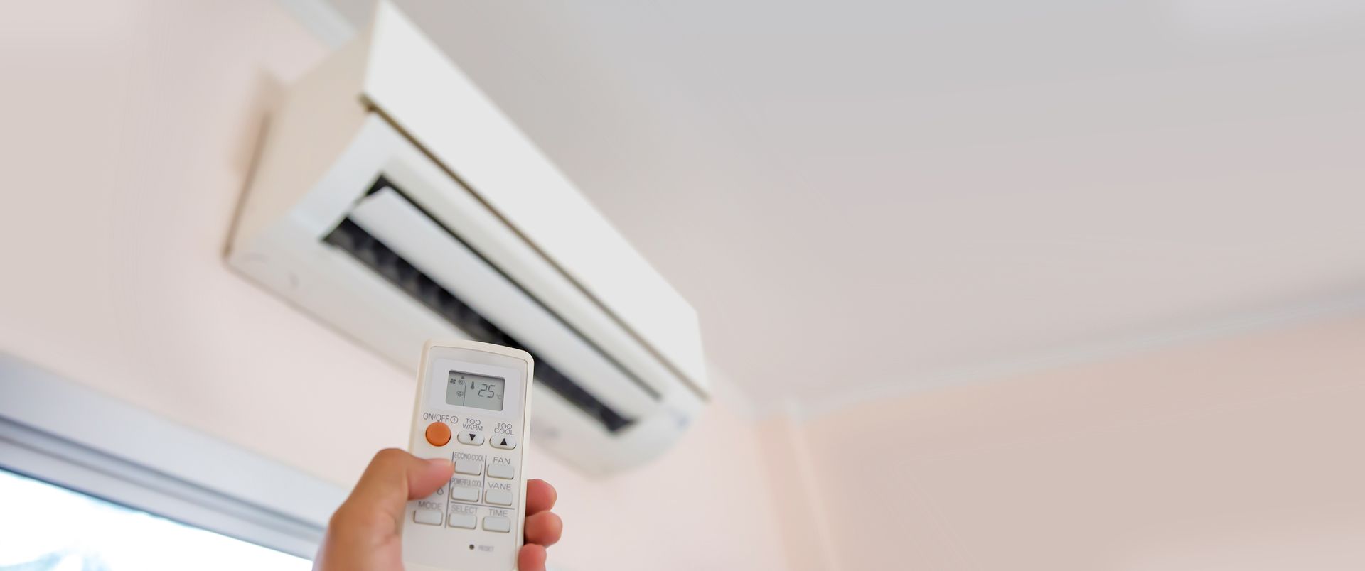 Une main commandant une télécommande de climatisation