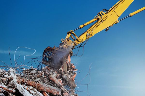 Una excavadora amarilla está recogiendo una pila de chatarra.