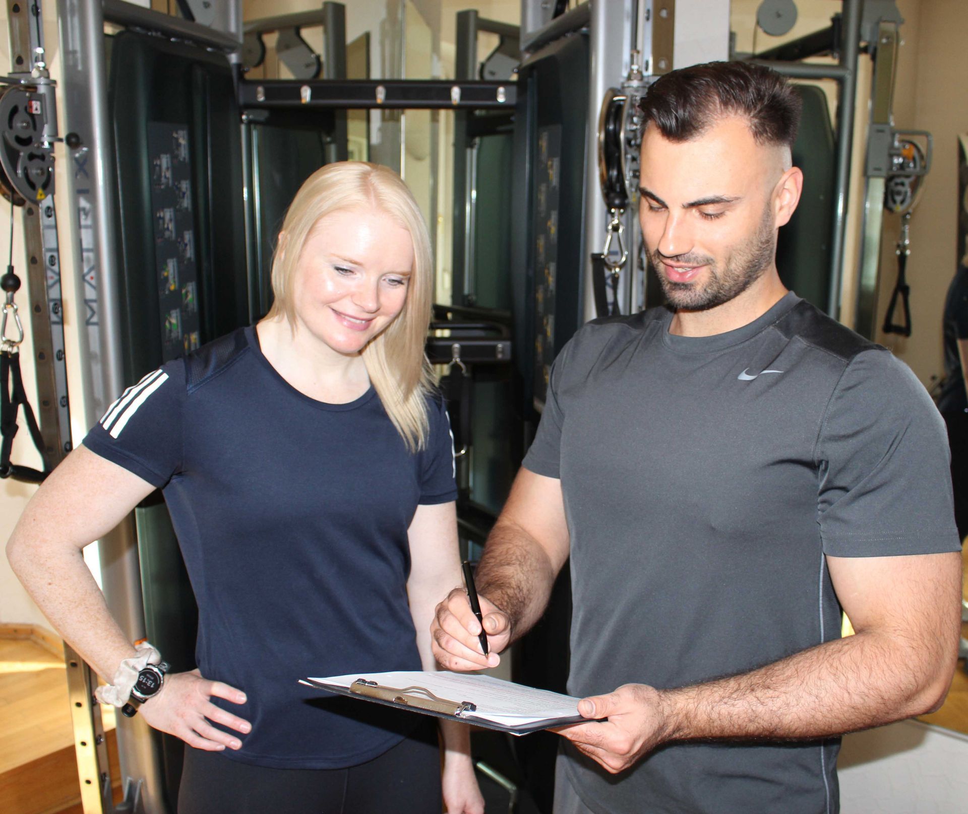 Ein Personaltrainer motiviert eine Kundin im Fitnessstudio.