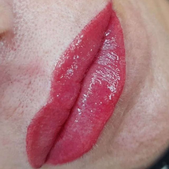 Primer plano de un tatuaje de labio de color rosa rojizo sobre piel clara, que muestra los contornos y el sombreado de los labios.