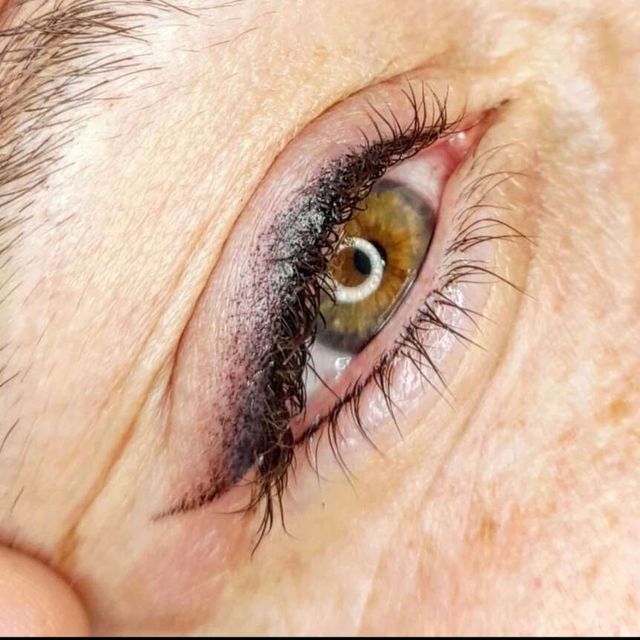 Primer plano de un ojo con delineador permanente en negro, iris verde-marrón y un toque de arrugas.