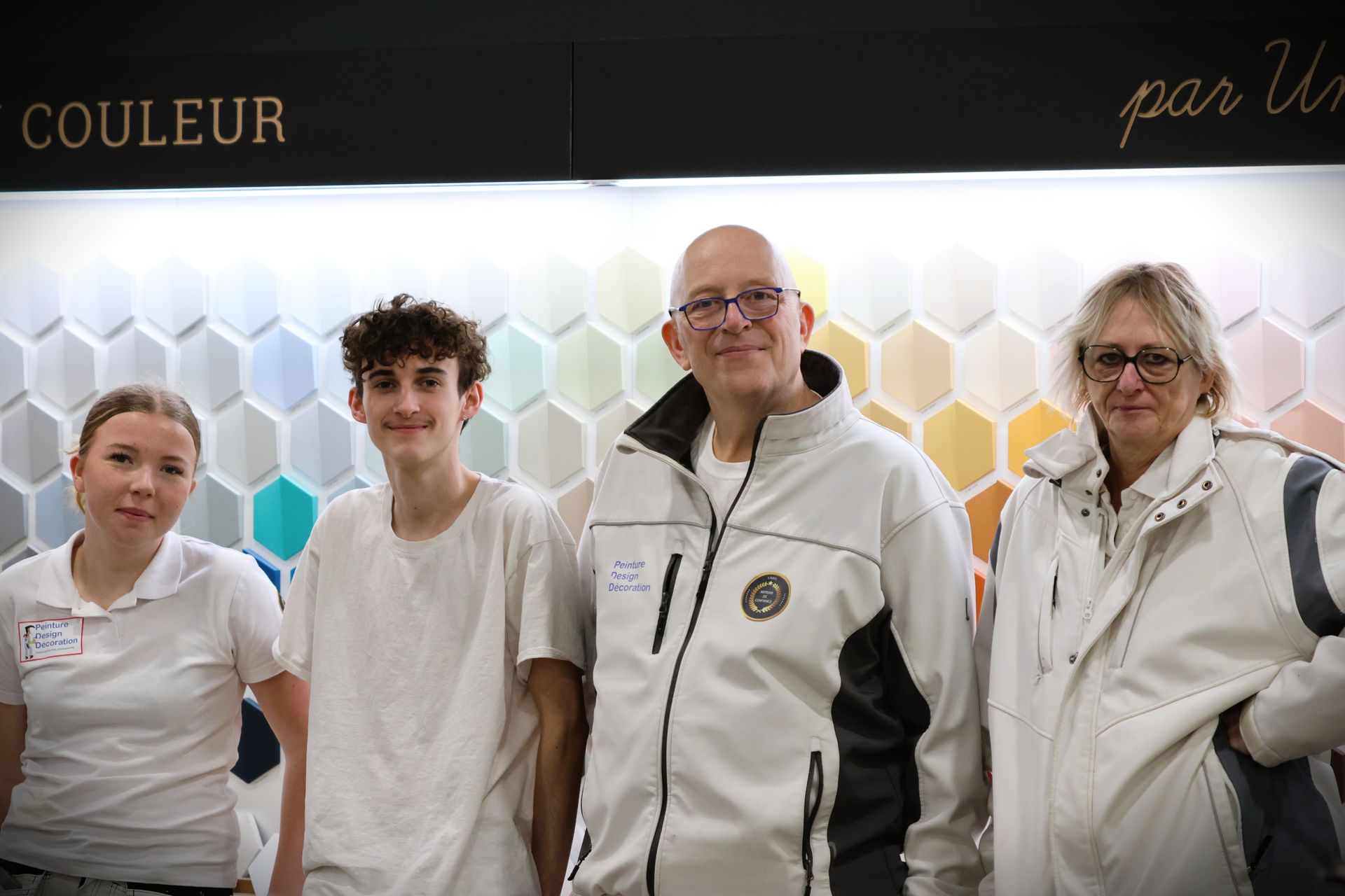 Quatre personnes se tiennent devant des échantillons de peinture.