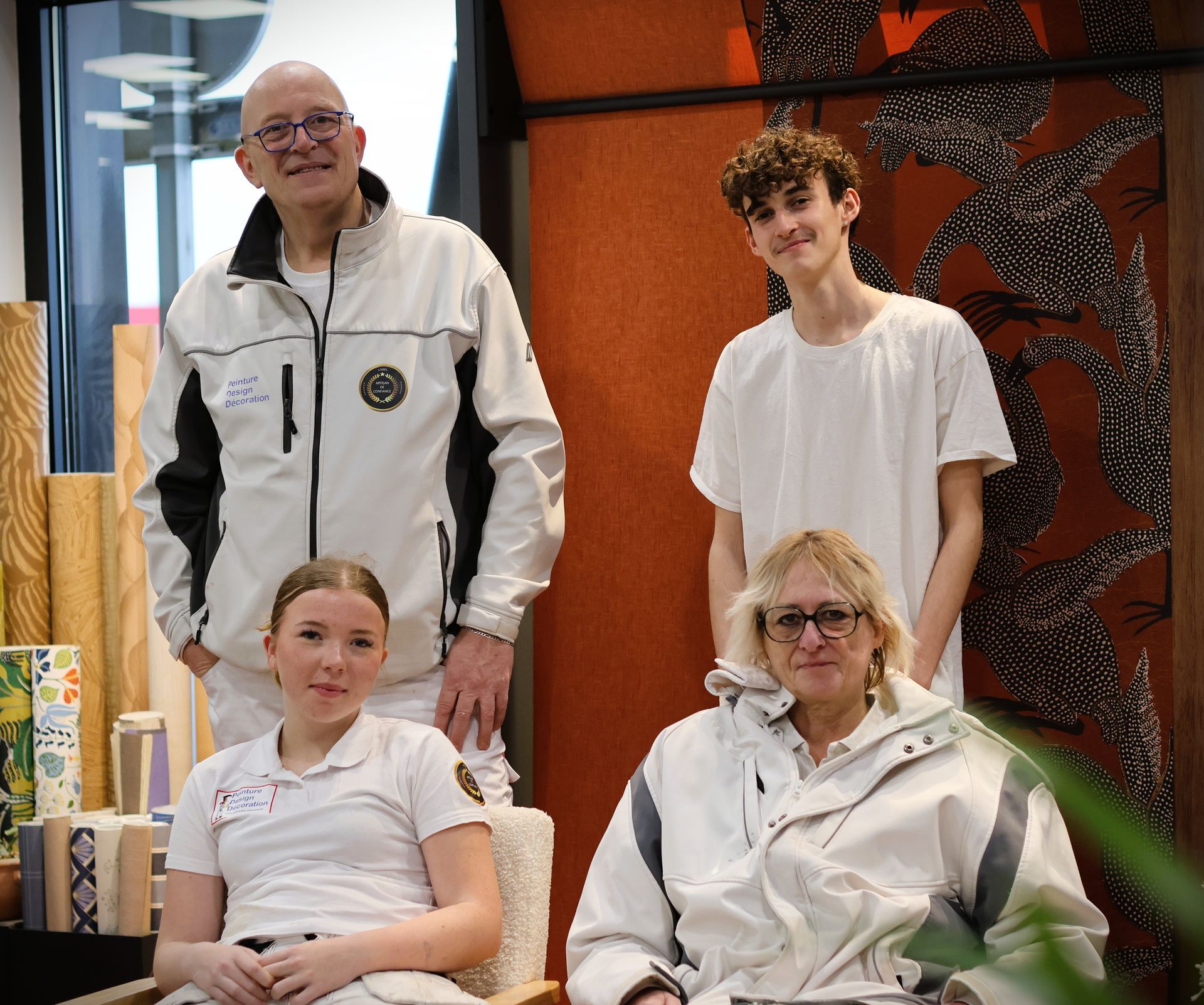 Quatre personnes de l'entreprise Peinture Design Décoration, habillées de blanc posent ensemble. 