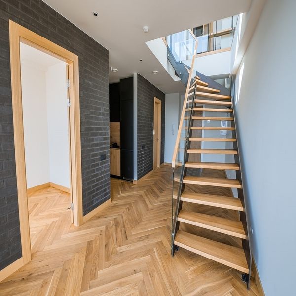 Un escalier en bois avec du parquet au sol.