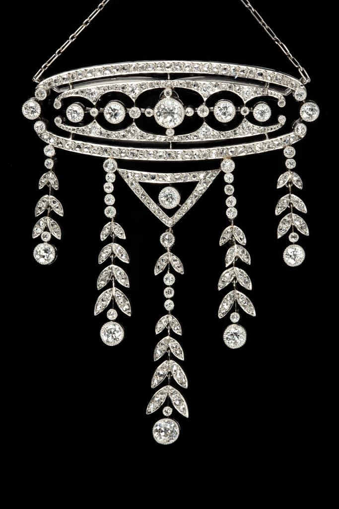 Un collier pendentif en diamant étincelant, au design symétrique de style Art déco, orné de délicats motifs de feuilles pendantes.