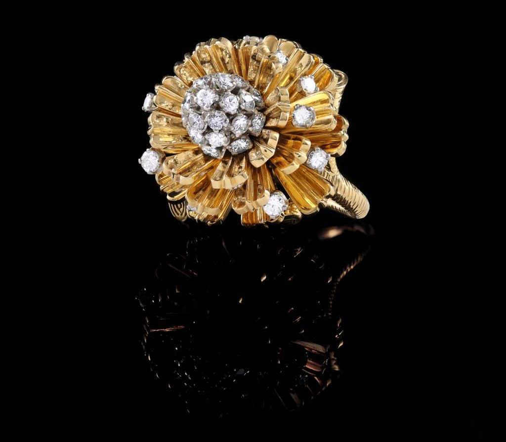 Une bague en or en forme de fleur, ornée d'un groupe de diamants au centre et de diamants supplémentaires sertis sur ses pétales.