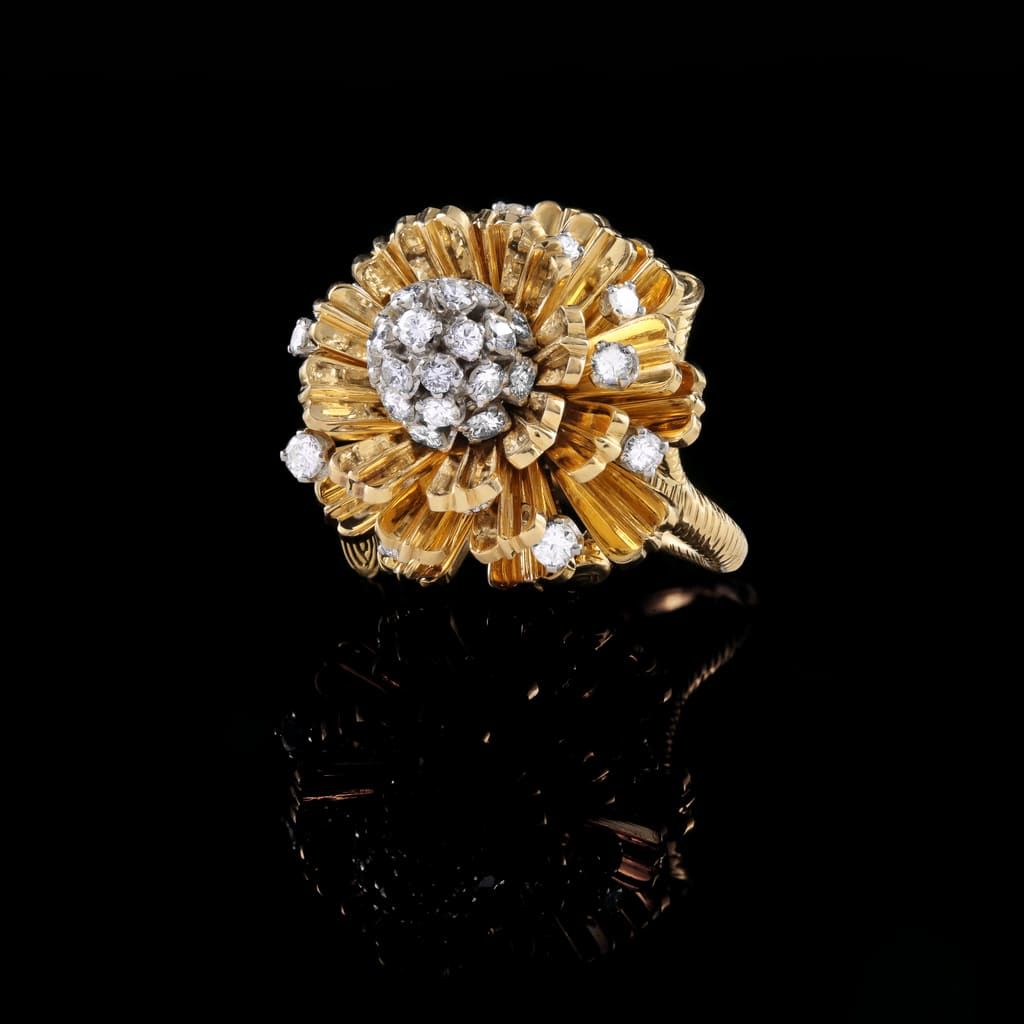Une bague cocktail en or en forme de fleur, ornée d'un centre serti de diamants et de diamants épars sur les pétales.