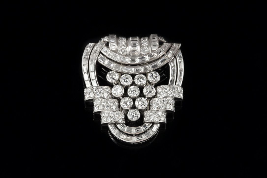 Broche vintage Art Déco en forme d'éventail géométrique à plusieurs niveaux, sertie de diamants sur un fond noir uni.