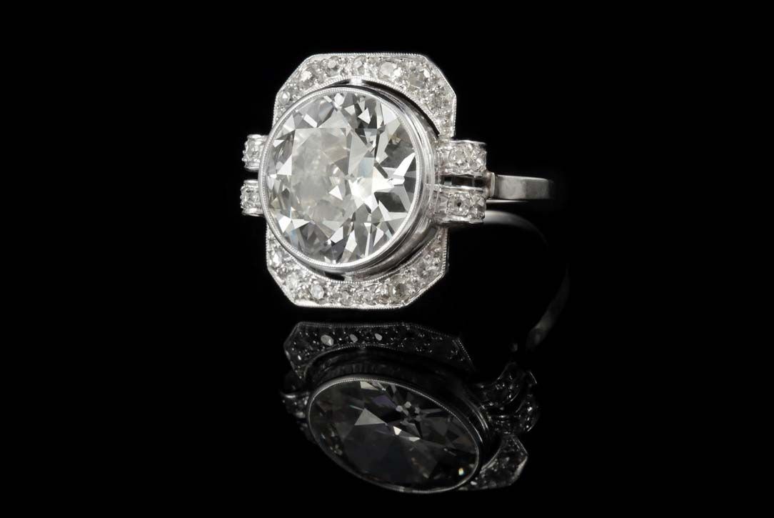 Une bague en diamant avec un sertissage halo octogonal et une pierre centrale de taille ronde, le tout se détachant sur un fond noir.