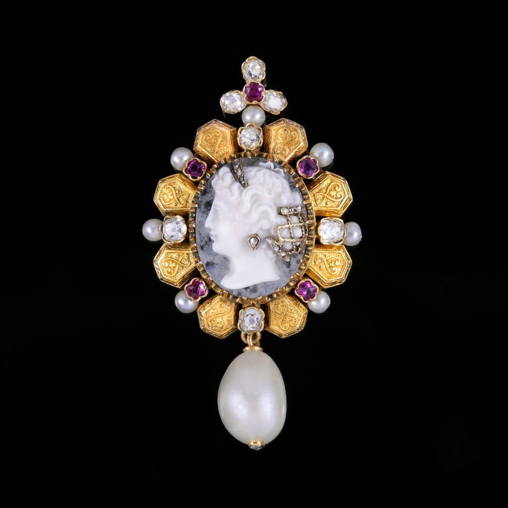 Broche en or ornée d'un camée central représentant un profil, entouré de perles, de rubis et de diamants, avec une grosse perle en forme de goutte.