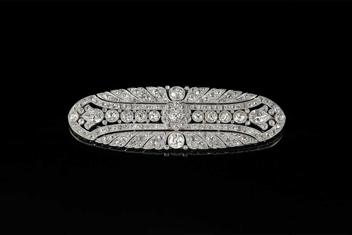 Broche ovale en diamant ornée d'un motif géométrique ajouré en filigrane sur fond noir.